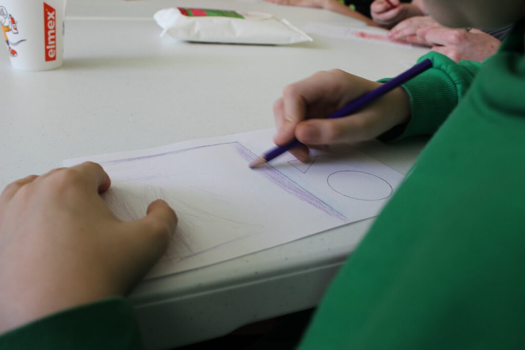 Діти розмальовують папір, з якого буде зроблено літаючий об'єкт. © Джоана Реттіг